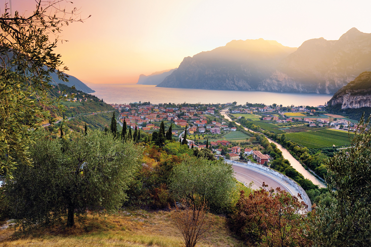 Scenic aerial view of Riva del Garda town, located on a shore of Garda lake, surronded by beautiful rocky mountains. Spectacular autumn sunset.